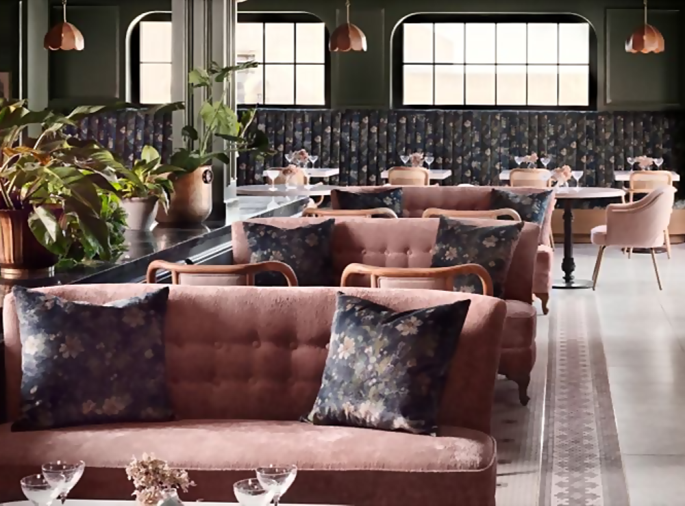 A hotel lounge with dusty pink loveseats is decorated in art deco style.