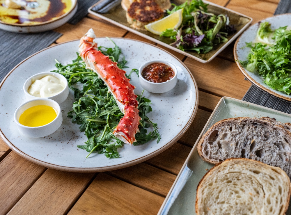 The Salish Signature Cut Alaskan King Crab Legs dish, among other plates, at The Restaurant & Terrace Bar. April 16, 2025