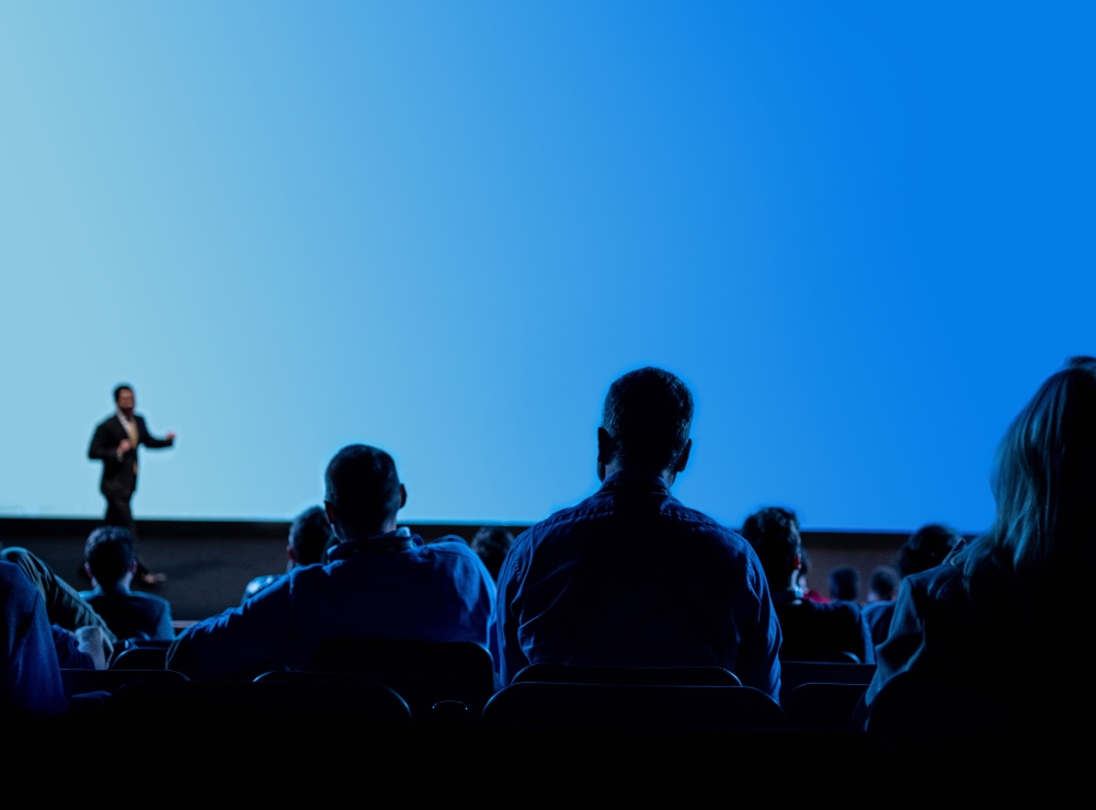 speaker on stage speaks to audience at conference